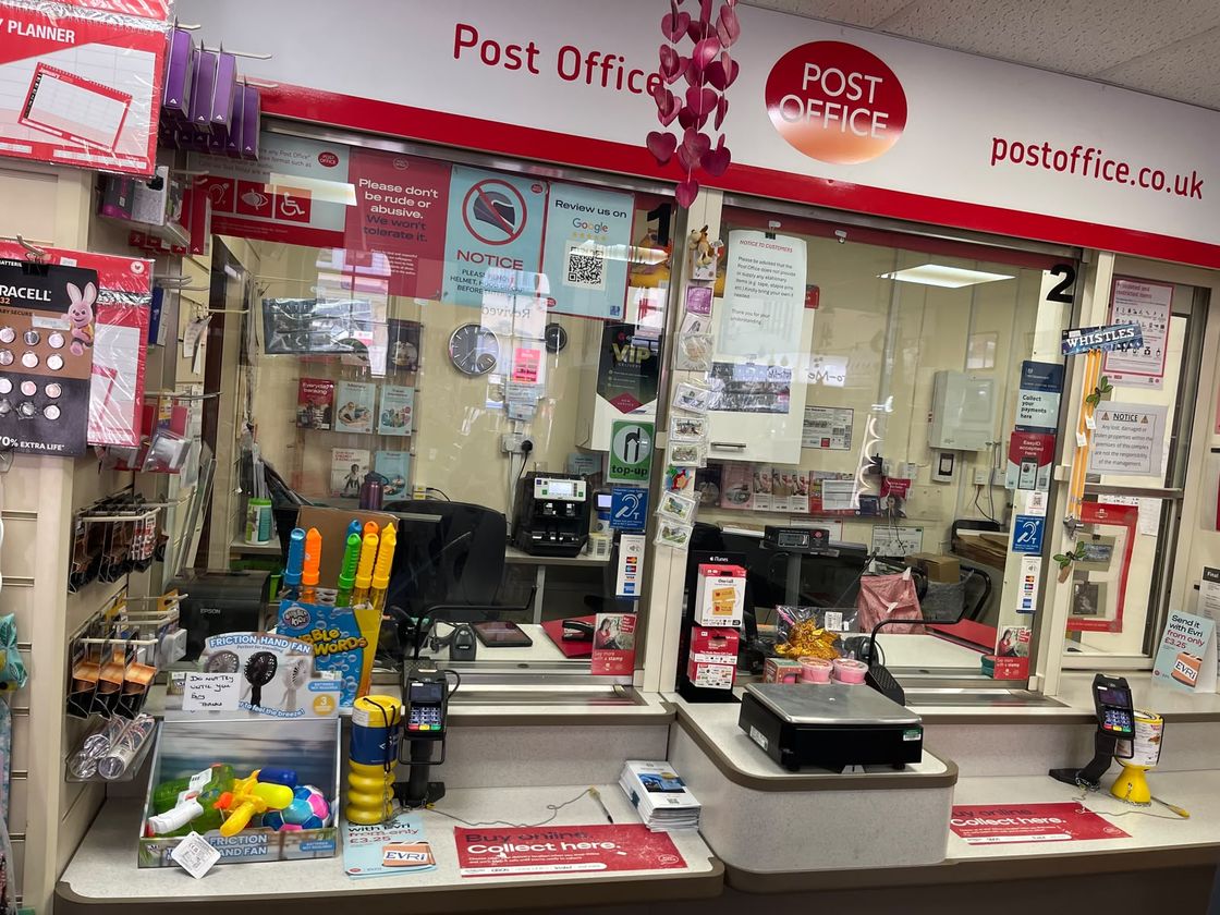 The two-position serving counter inside Newport Pagnell Post Office, with Evri collection points and card terminals